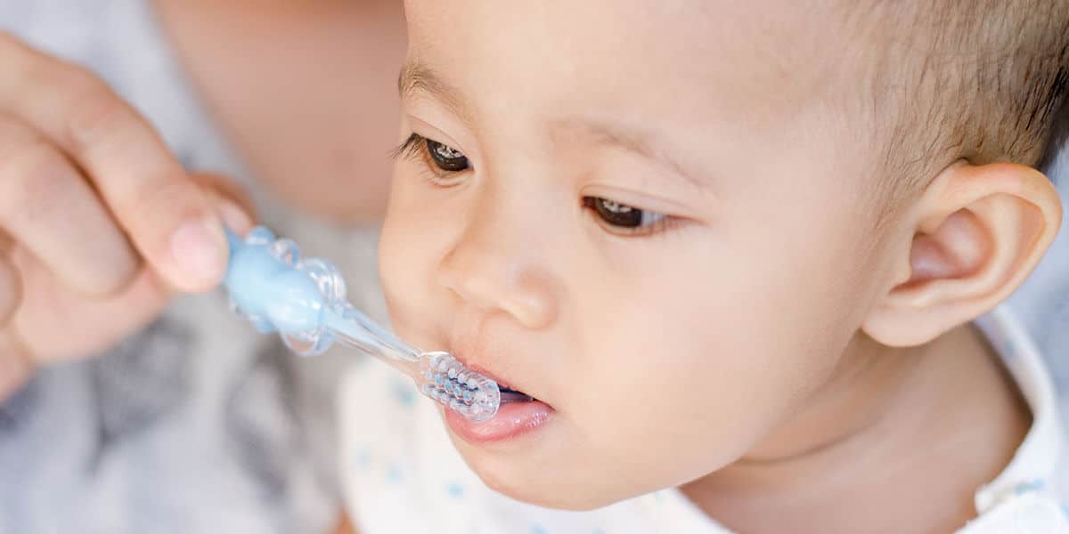 Toddler brushing teeth with parent