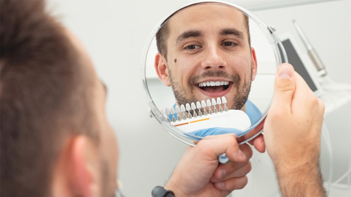 Man Smiling in Mirror after Teeth Whitening